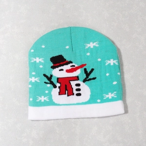 Detailed view of turquoise knitted Christmas hat featuring white snowflake patterns and a snowman