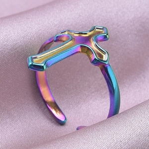 Rainbow cross open ring displayed on smooth purple satin fabric with metal luster