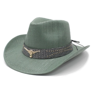 Macro detail of sage green straw cowboy hat featuring a golden bull head metal accent