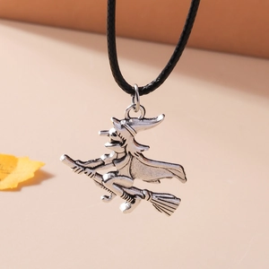 Macro shot of silver witch on broom pendant with black braided leather necklace cord