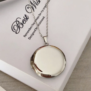 Macro view of polished silver stainless steel round locket pendant on a delicate chain