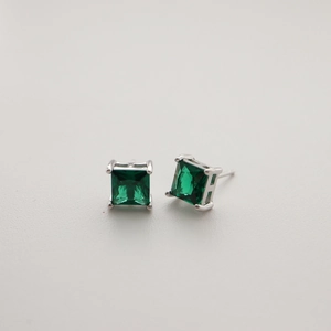 Detailed close-up of square emerald green cubic zirconia earrings in silver prong setting