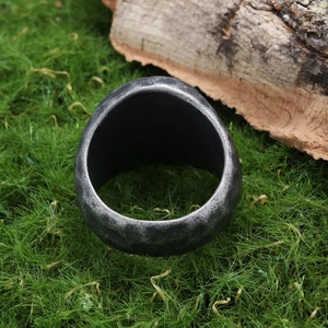 Detail shot of vintage silver compass ring on tree bark with engraved Norse runes texture