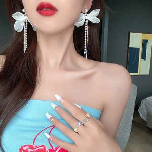 Élégantes boucles d'oreilles longs nœuds avec glands perles et maille sur modèle