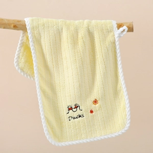Detail of yellow coral fleece towel with duck embroidery hanging on a wooden branch