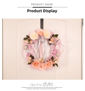 Detail showing artificial pink and white rose wreath with ribbon on a white wooden door