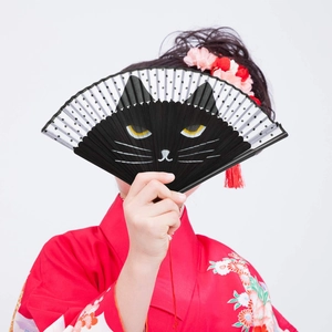 Japanese style black folding fan featuring a cat face pattern held by woman in kimono