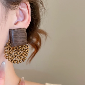 Detail of vintage wooden geometric earrings with beads worn by a model in warm light