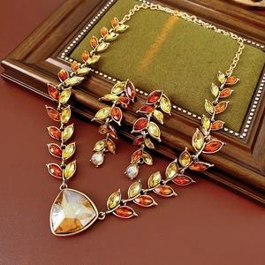 Détail d'un ensemble de bijoux vintage dorés avec cristaux ambrés et pendentif feuille