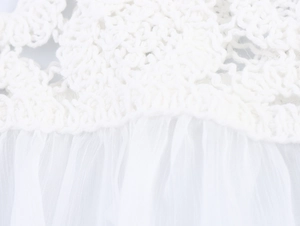 Close-up of white sweet French top featuring crochet lace stitching and sheer pleated fabric