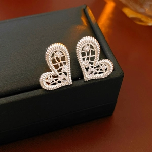 Macro detail of silver heart stud earrings with cubic zirconia on black jewelry box