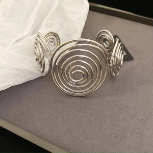 Macro shot of silver wave spiral cuff bracelet showing polished metallic texture