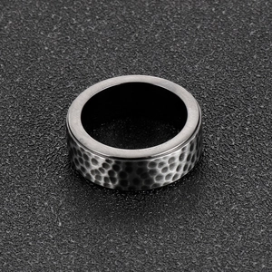 Detailed macro view of 8mm black hammered finish titanium steel ring with industrial texture