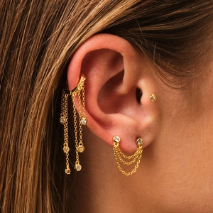 Detail of gold tassel chain earrings with shimmering crystals on a model's ear