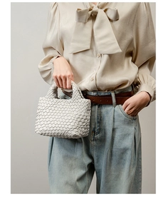 Detailed view of hand-woven white leather bucket bag styled with a silk bow blouse