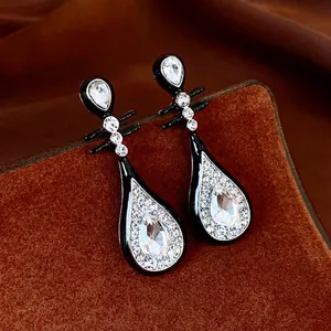 Silver needle Pipa earrings with black enamel and sparkling diamonds on brown display