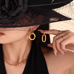 Golden geometric hoop earrings and necklace set with vintage textured details on a model