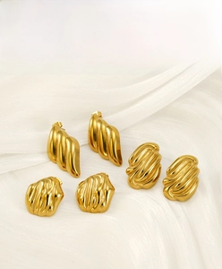 Macro shot of 18K gold-plated irregular textured earrings on white silk fabric background