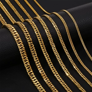 Close-up of golden stainless steel cuban link chains in various widths on leather surface