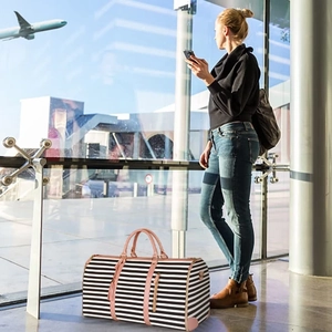 Spacious striped travel bag with pink accents shown in an airport terminal setting