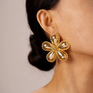 Vue macro de grandes boucles d'oreilles fleurs dorées avec finition polie sur modèle