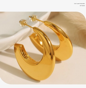 Macro shot of 18K gold plated C-shaped geometric earrings on a white ceramic base