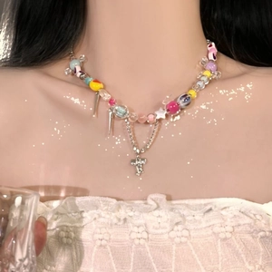 Close-up of colorful heart beads and silver cross pendant necklace worn with lace dress