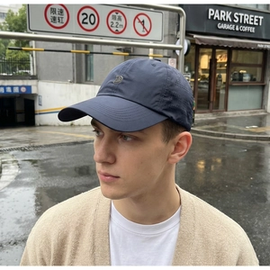 Dettaglio cappello blu navy con logo D in metallo e fori di ventilazione a taglio laser