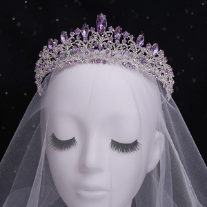 Close-up of bridal crystal crown with purple gemstones and white wedding veil decoration