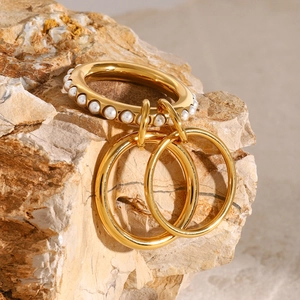 Stacked gold pearl rings on natural stone background showcasing luxury stainless steel design