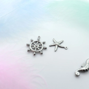 Macro shot of silver stainless steel charms featuring rudder, starfish, and seahorse shapes