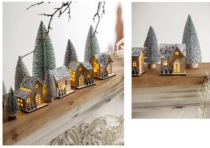 Detail of glowing LED wooden Christmas houses and mini snow cedars for table decor
