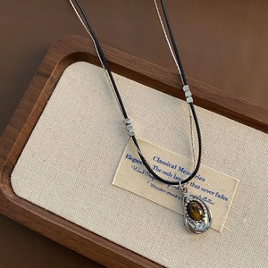 Double-layered vintage necklace with tiger eye stone and silver tone pendant on wood background