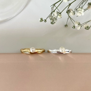 Macro shot of gold and silver wave rings with pearls on a soft velvet surface