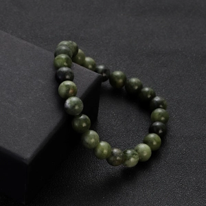 Macro view of dark green natural stone beads on a sleek black display box
