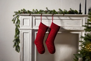 Detail showing deep red chunky knit Christmas stocking with honeycomb texture on fireplace