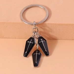 Macro shot of three dark gothic coffin charms with silver crosses on a metal keychain