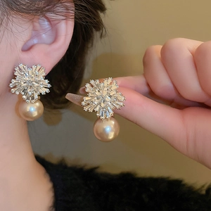 Elegant flower-shaped zircon stud earrings with hanging pearl on a model's ear