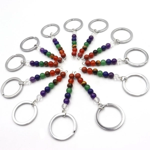 Radial arrangement of 12 natural chakra stone beaded keychains on a white background