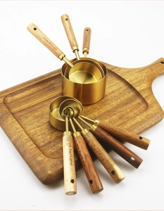 Detailed view of 8-piece gold stainless steel measuring set with acacia wood handles