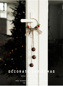 Christmas door hanging with vintage metal bells, plaid bow, and red berries on a white door