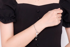 Bracelet à breloques cœur et clé en argent porté au poignet avec chaîne ajustable