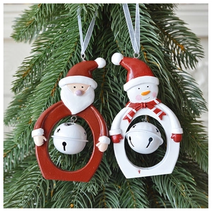 Close-up of resin Santa and snowman ornaments with white bells on a Christmas tree