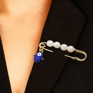 Détail de la broche Main de Fatma avec perles et œil protecteur sur un revers noir