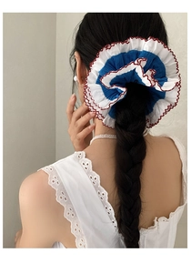 Detailed back view of a large blue and white lace scrunchie with red stitching trim