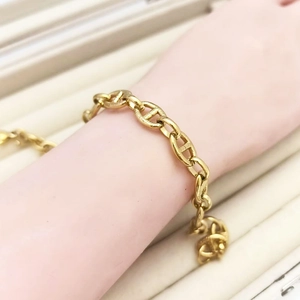 Detailed view of bold golden pig-nose link chain bracelet on a jewelry display stand