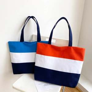 Detail of color-blocked canvas tote bags in blue-white and orange-white striped designs