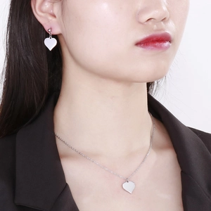 Polished silver heart pendant necklace and stud earrings set on a female model