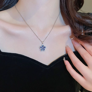 Detailed view of a silver floral necklace with blue zircon petals on a model neckline