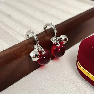 Close-up of S925 sterling silver earrings with red beads on a wooden jewelry stand